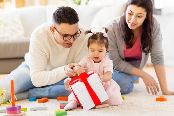 Baby girl with birthday gift and parents at home — Stock Photo, Image