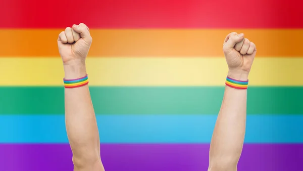 Manos con gay orgullo arco iris pulseras muestra puño — Foto de Stock