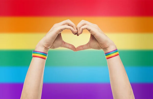 Male hands with gay pride wristbands showing heart — Stock Photo, Image