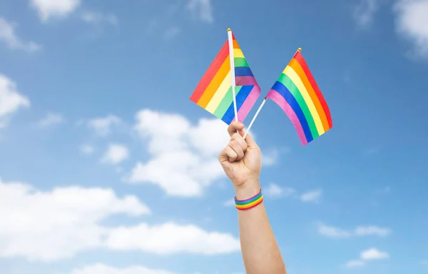 Hand with gay pride rainbow flags and wristband — Stock Photo, Image