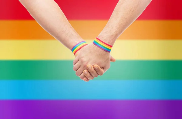 Mani di coppia con gay orgoglio arcobaleno braccialetti — Foto Stock