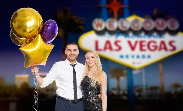 Feliz pareja con gorras de fiesta y globos — Foto de Stock