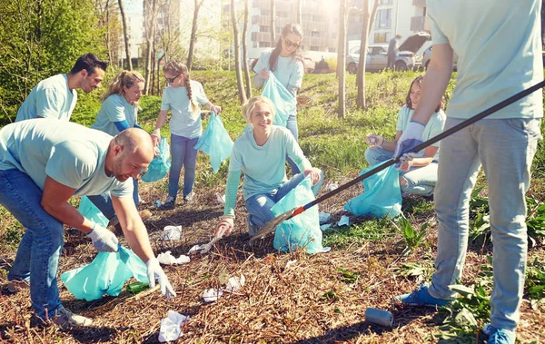 Relawan dengan kantong sampah membersihkan area taman — Stok Foto