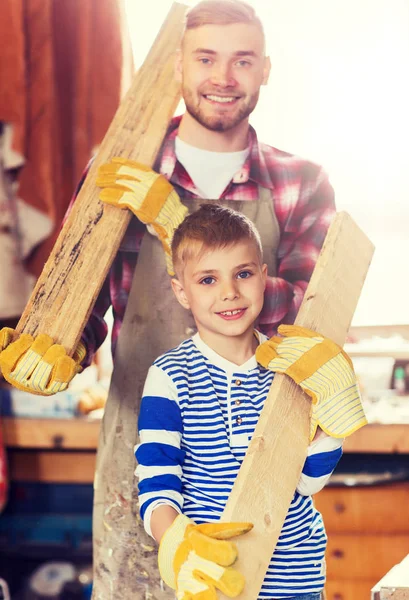 Pai feliz e filho com prancha de madeira na oficina — Fotografia de Stock