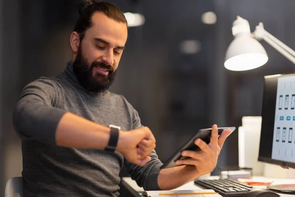 Man met smartwatch en tablet pc bij nacht kantoor — Stockfoto