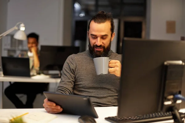 Человек с планшетным ПК, пьющий кофе в офисе — стоковое фото