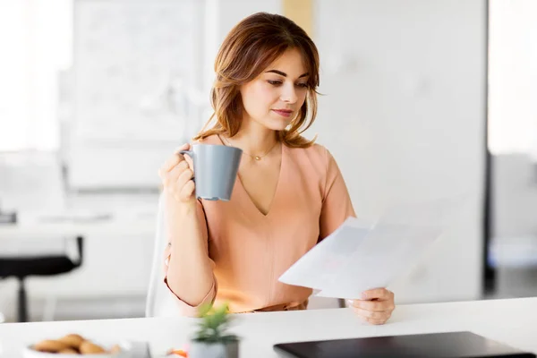 Bizneswoman z dokumentami pije kawę w biurze — Zdjęcie stockowe