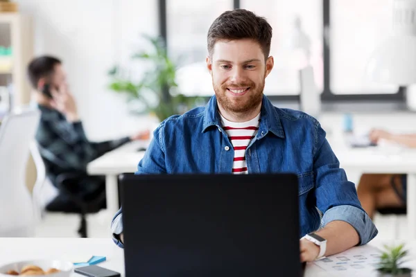 Sonriente hombre creativo con portátil de trabajo en la oficina —  Fotos de Stock