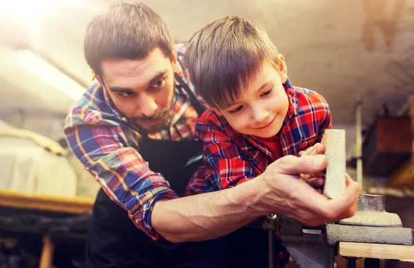 Padre e hijo pequeño con tablón de madera en el taller —  Fotos de Stock