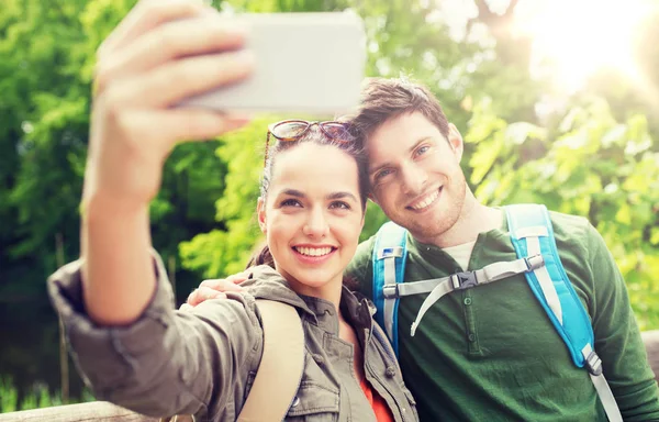 Echtpaar met rugzakken selfie te nemen door smartphone — Stockfoto