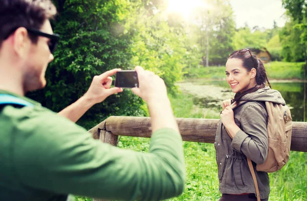 Пара с рюкзаками, фотографирующими на смартфон — стоковое фото