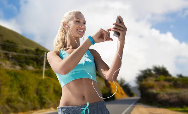 Femme avec smartphone et écouteurs faisant du sport — Photo