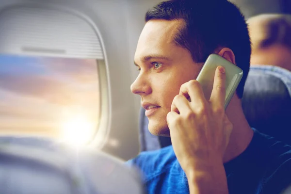 Молодий чоловік дзвонить на смартфон у літаку — стокове фото