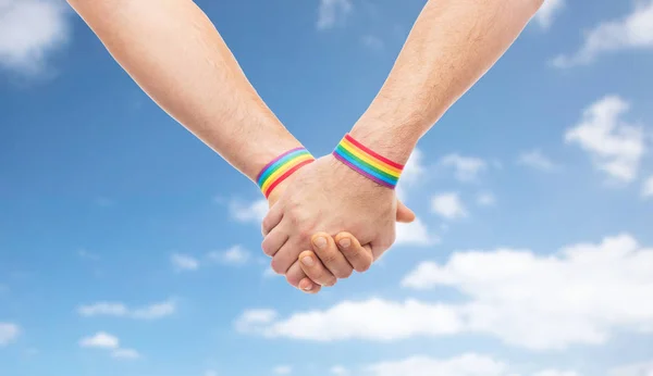 Mani di coppia con gay orgoglio arcobaleno braccialetti — Foto Stock