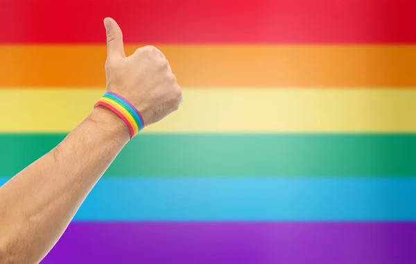 Mano con gay orgullo arco iris pulsera espectáculos pulgar — Foto de Stock
