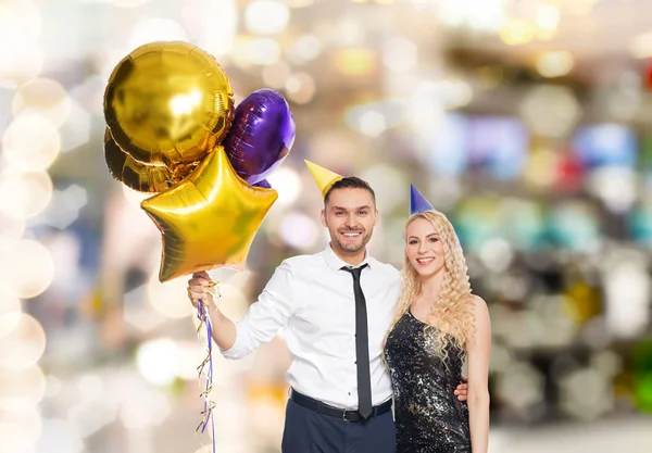 Счастливая пара с воздушными шарами над огнями вечеринки — стоковое фото