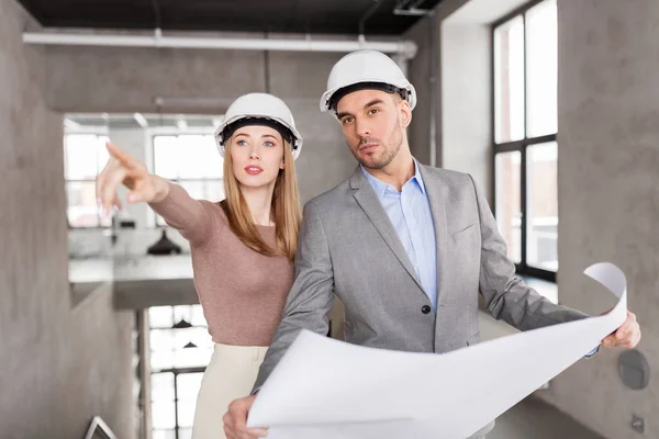 Architects with blueprint and helmets at office — Stock Photo, Image