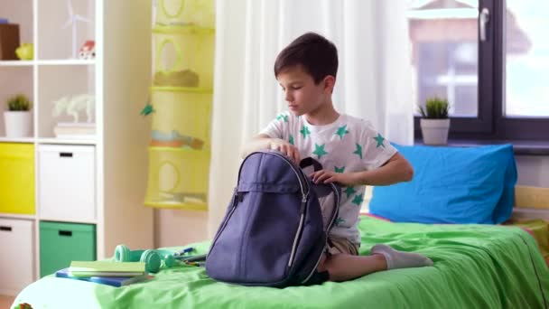 Pojke förpackning skolväska med skolmaterial hemma — Stockvideo