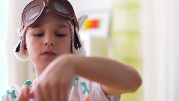 Menino em chapéu piloto brincando com brinquedo de avião em casa — Vídeo de Stock