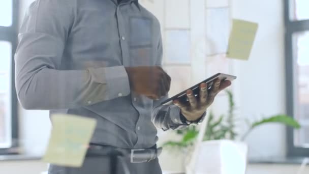 Бизнесмен с планшетным ПК на стене офиса стекло — стоковое видео