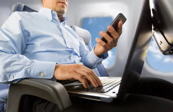 Uomo d'affari con smartphone e laptop in aereo — Foto Stock