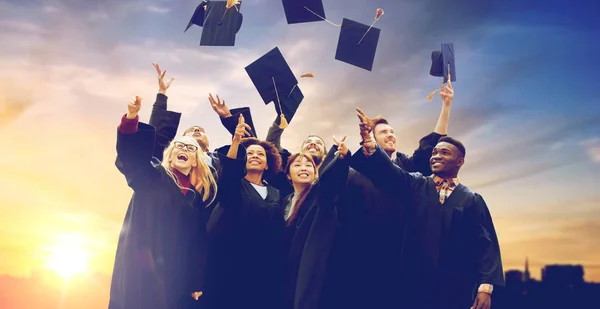 Happy graduates or students throwing mortar boards — Stock Photo, Image