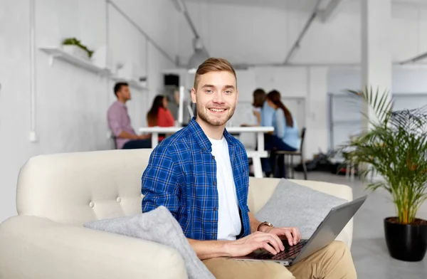 Uomo sorridente con computer portatile che lavora in ufficio — Foto Stock