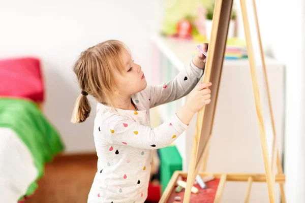 Щаслива дівчинка малює на крейдяній дошці вдома — стокове фото
