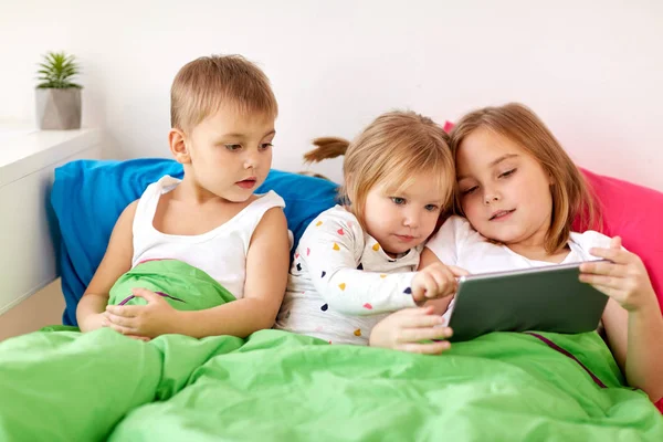 Little kids with tablet pc in bed at home — Stock Photo, Image