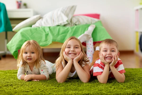 Happy little kids lying on floor or carpet — Stock Photo, Image