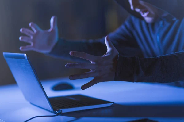 Arga hacker med laptop skriker i mörkt rum — Stockfoto