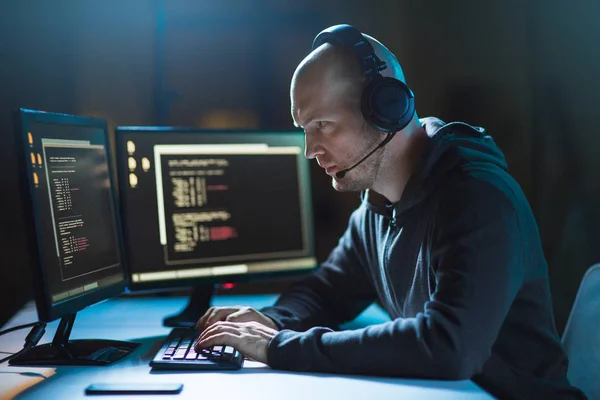 Hacker com computador e fone de ouvido no quarto escuro — Fotografia de Stock