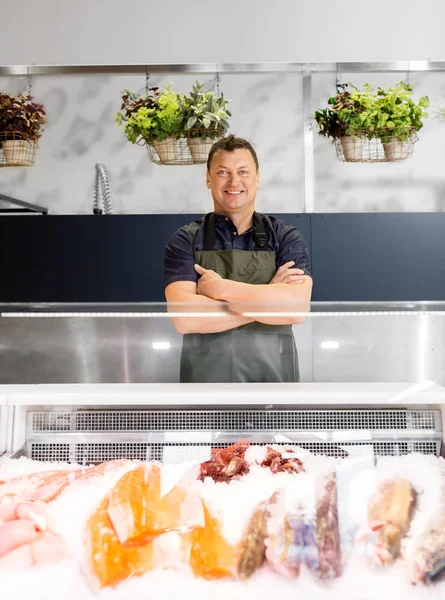 Male seller with seafood at fish shop fridge — Stock Photo, Image