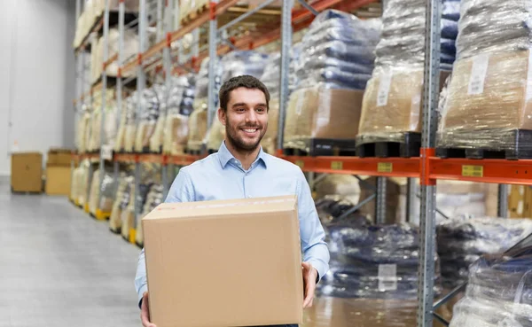 Homem feliz com caixa de papelão pacote no armazém — Fotografia de Stock