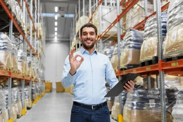 Businessman with clipboard at warehouse showing ok — Stock Photo, Image