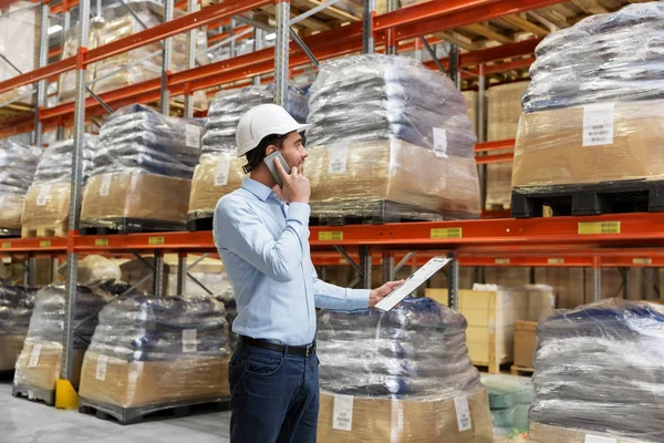 Businessman calling on smartphone at warehouse — Stock Photo, Image