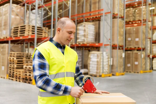 Warehouse worker packing parcel with scotch tape — Stock Photo, Image