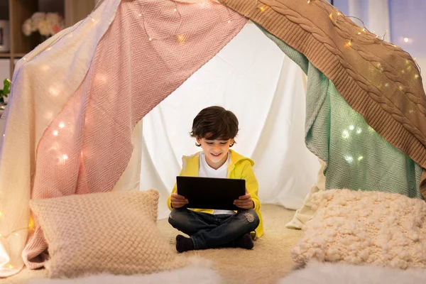 Маленький мальчик с планшетным ПК в детской палатке дома — стоковое фото