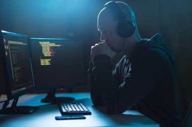 hacker with coding on laptop computer in dark room clipart