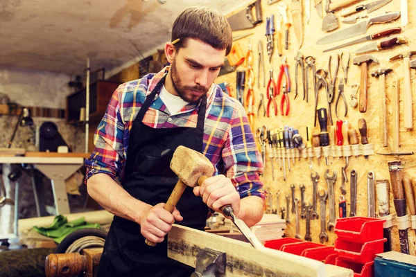 Плотник с деревом, молотком и зубилом в мастерской — стоковое фото
