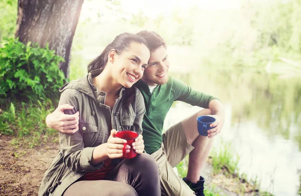 Счастливая пара с чашками пить в природе — стоковое фото