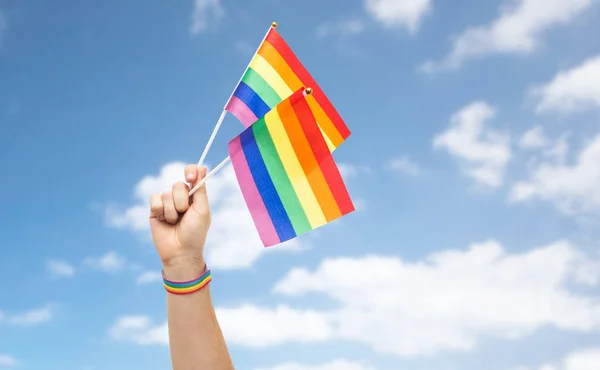 Mão com orgulho gay arco-íris bandeiras e pulseira — Fotografia de Stock