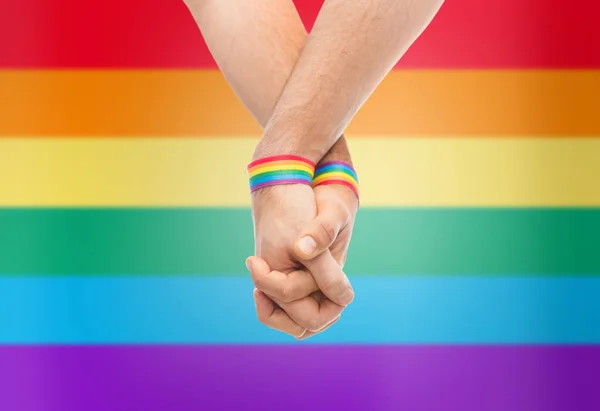 Hands of couple with gay pride rainbow wristbands — Stock Photo, Image