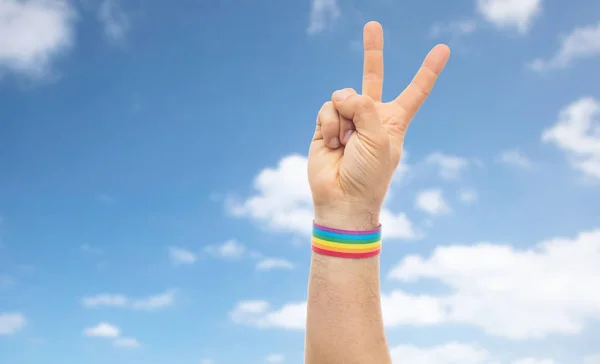 Mano con gay orgullo arco iris pulsera hacer la paz — Foto de Stock