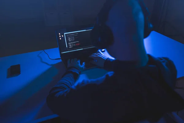 Hacker con codificación en el ordenador portátil en la habitación oscura — Foto de Stock