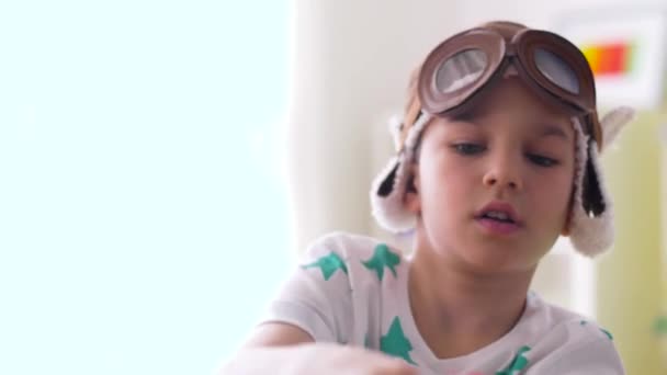 Chico en piloto sombrero jugando con avión juguete en casa — Vídeos de Stock