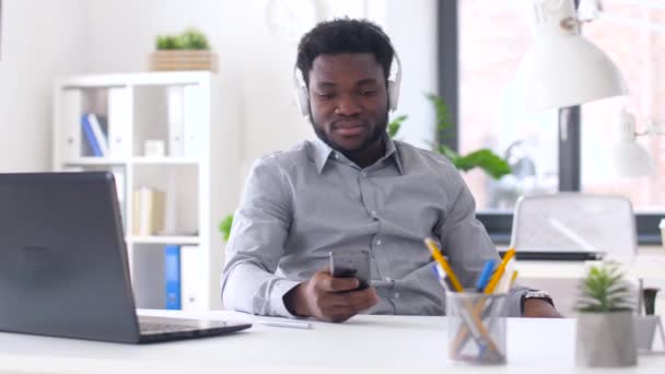 Homem de negócios com fones de ouvido e smartphone — Vídeo de Stock