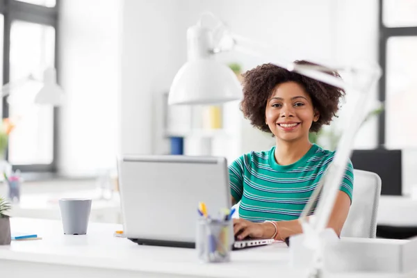 Mujer africana feliz con ordenador portátil en la oficina — Foto de Stock