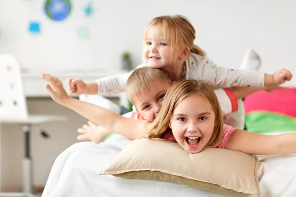 Niños pequeños felices divirtiéndose en la cama en casa — Foto de Stock