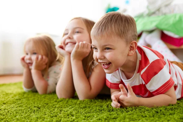 Niños pequeños y felices tumbados en el suelo o la alfombra —  Fotos de Stock